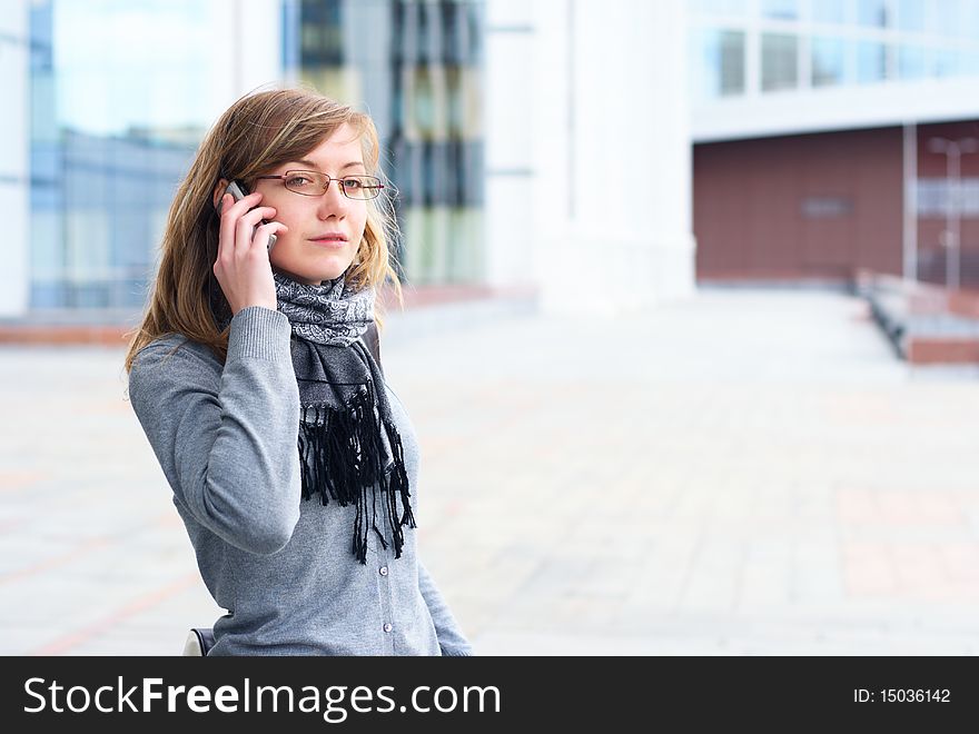 The young girl in glasses, talks by a mobile phone. The person close up. The young girl in glasses, talks by a mobile phone. The person close up
