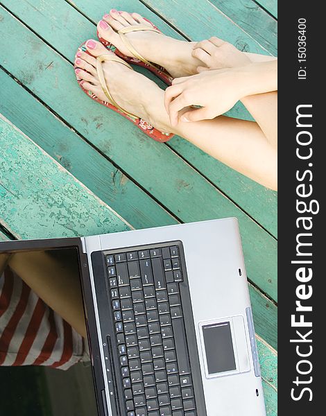 Women's hands and feet next to the laptop on a wooden staircase. Top view. Women's hands and feet next to the laptop on a wooden staircase. Top view