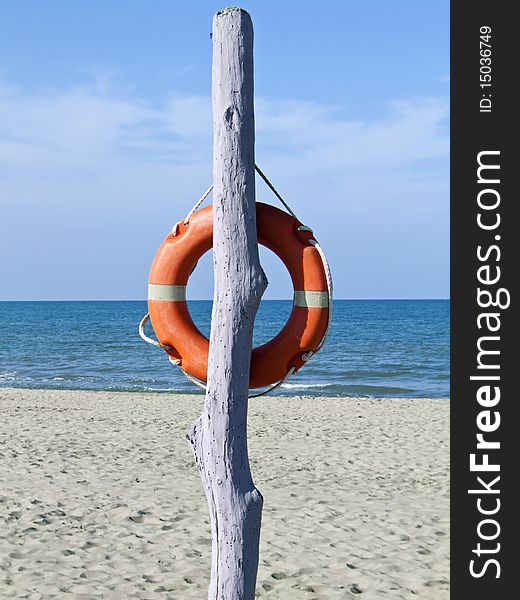 Violet safe pole with orange lifebelt on a solitary beach. Violet safe pole with orange lifebelt on a solitary beach
