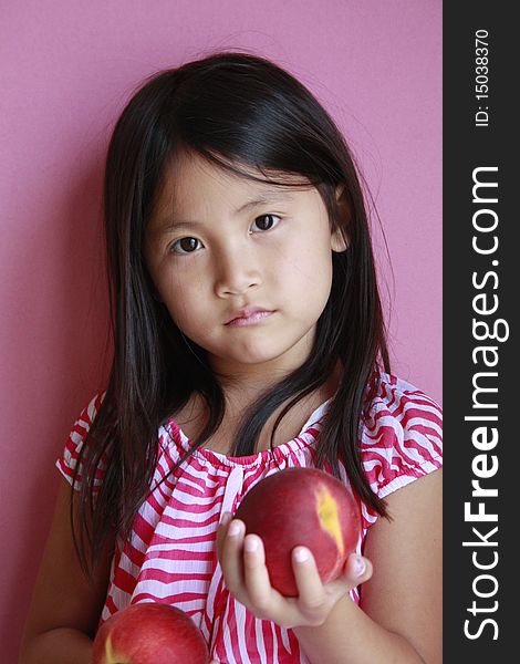 Little asian girl holding peaches with suprised look. Little asian girl holding peaches with suprised look