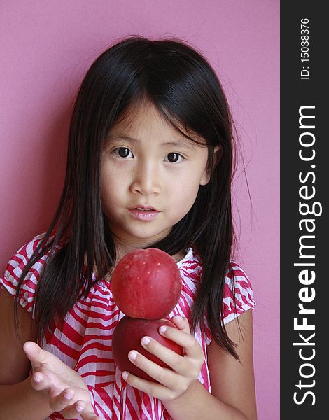 Little asian girl holding peaches with suprised look. Little asian girl holding peaches with suprised look