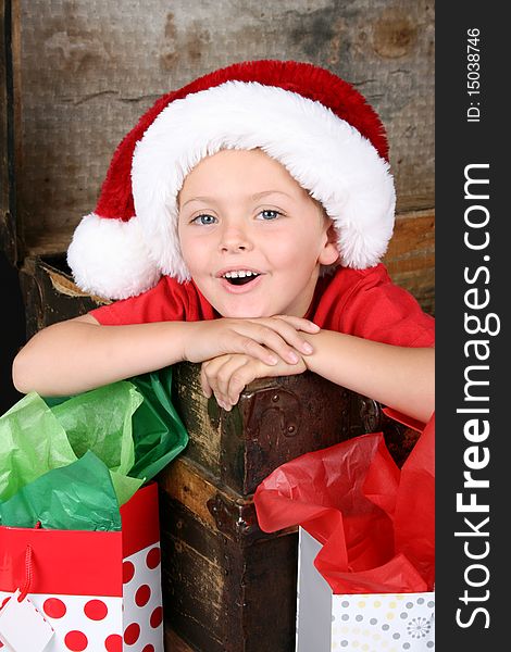 Young boy sitting inside an antique trunk wearing a christmas hat. Young boy sitting inside an antique trunk wearing a christmas hat