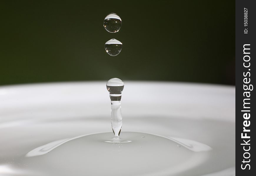 A water drop splashing in a cup of water. A water drop splashing in a cup of water