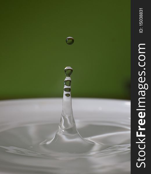 A water drop splashing in a cup of water. A water drop splashing in a cup of water