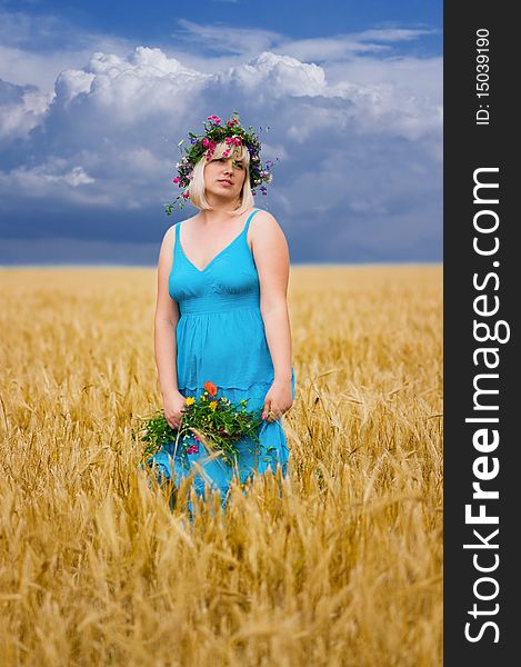 Beautiful woman in wreath of wild flowers in wheat meadow on sunny day. Beautiful woman in wreath of wild flowers in wheat meadow on sunny day