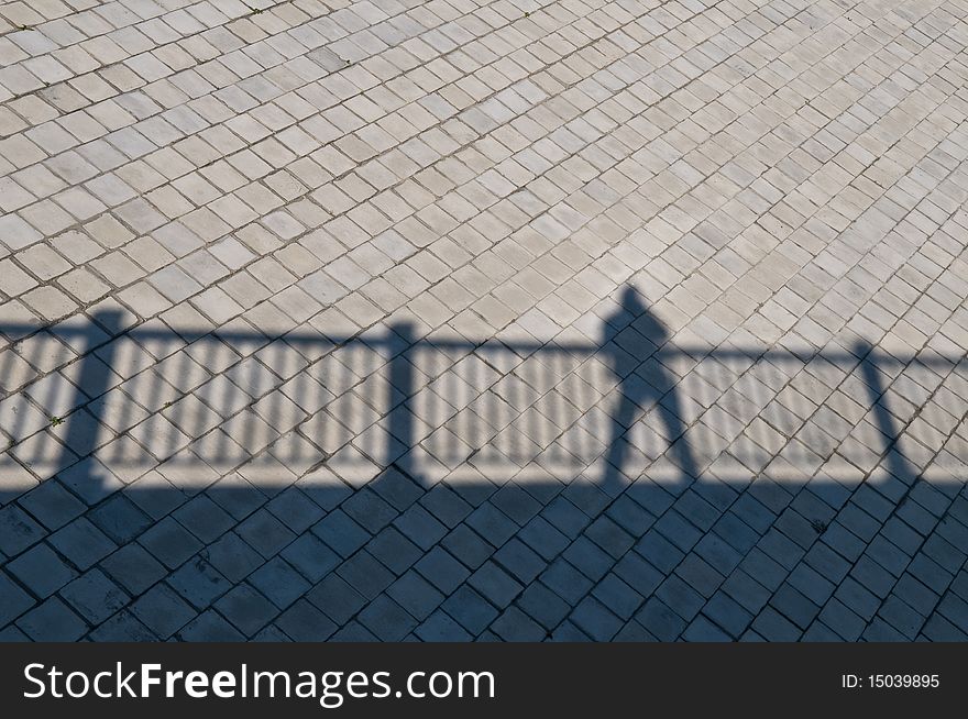 A shadow of a railing over a bridge with man standing. A shadow of a railing over a bridge with man standing