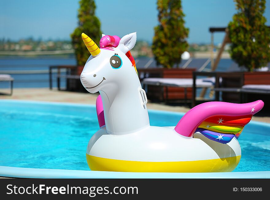 Funny inflatable unicorn ring floating in swimming pool on sunny day