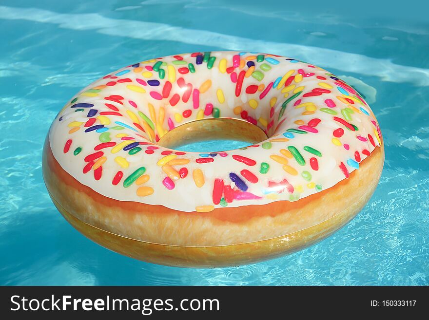 Bright inflatable doughnut ring floating in swimming pool