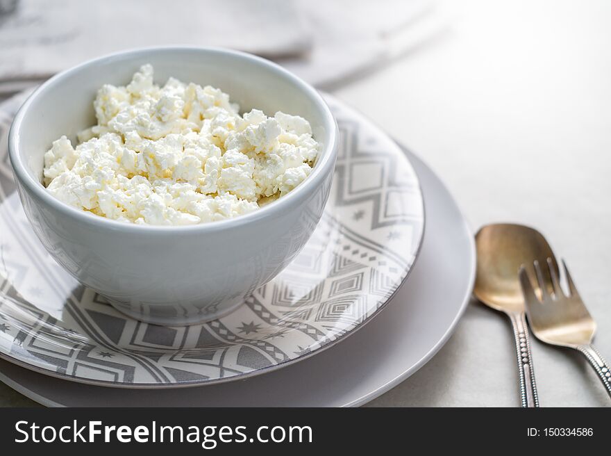 Cottage cheese on a white bowl on a gray background