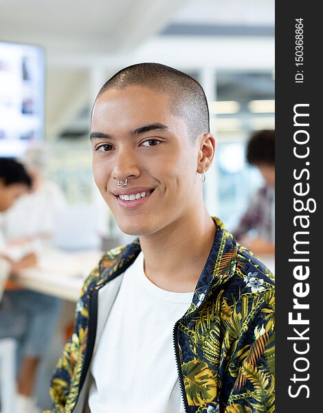 Portrait of mixed race male fashion designer sitting in the conference room while diverse business people discussing at office. Portrait of mixed race male fashion designer sitting in the conference room while diverse business people discussing at office