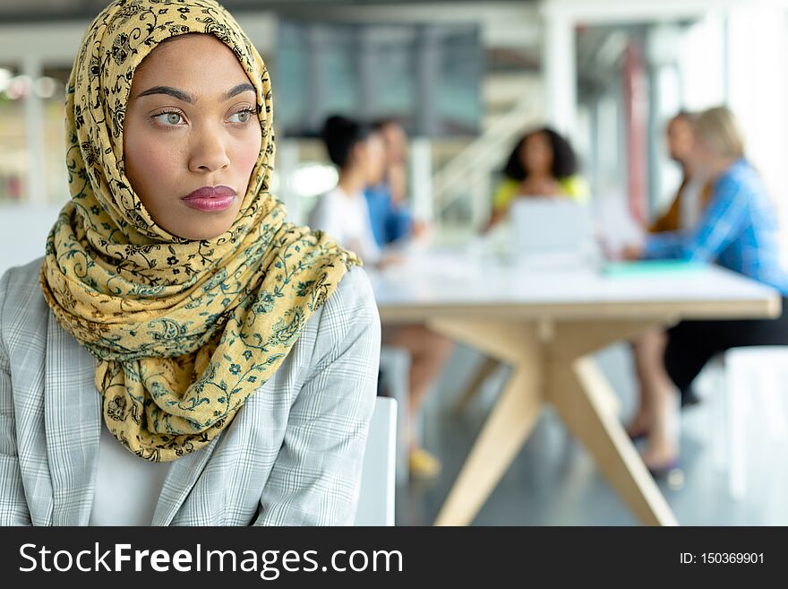 Businesswoman in hijab looking away at conference room in a modern office