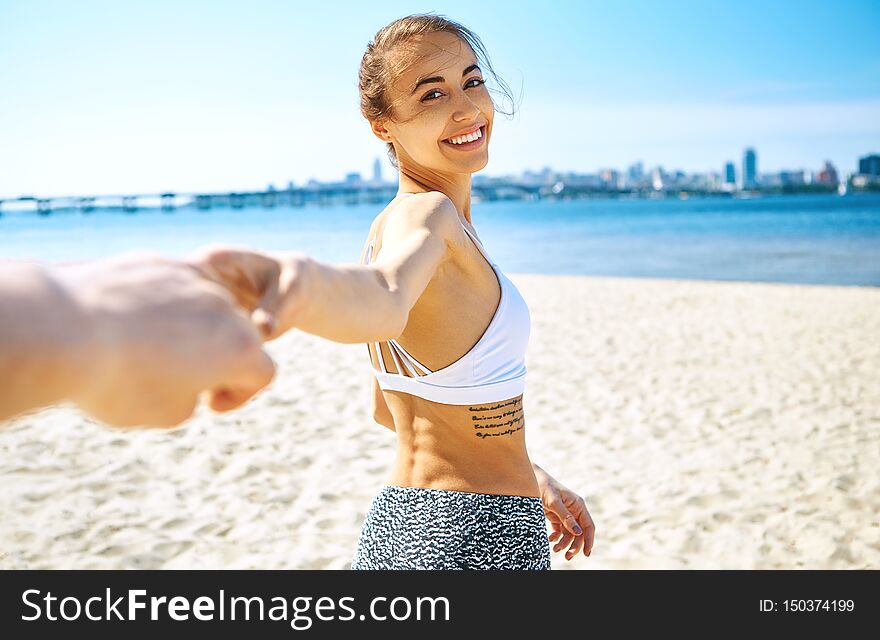 Portrait Of Beautiful Sexy Happy Woman On The Sand City Beach With Sea Background Is Holding Someone Hand. Summertime