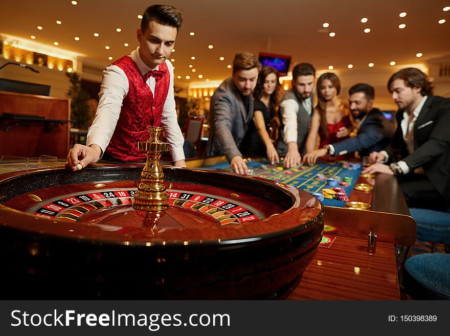 The Croupier Holds A Roulette Ball In A Casino In His Hand.