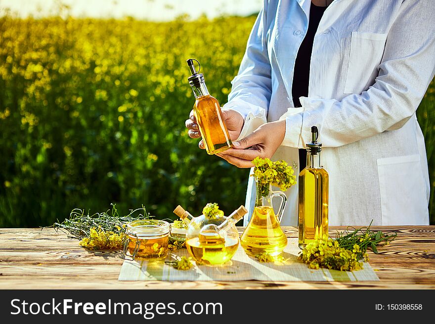 Rapeseed oil bottle in hand of an agronomist or biologist on background rape  field