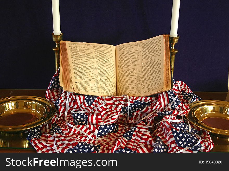 Patriotic church display consisting of a Bible, flag, candles and offering plates