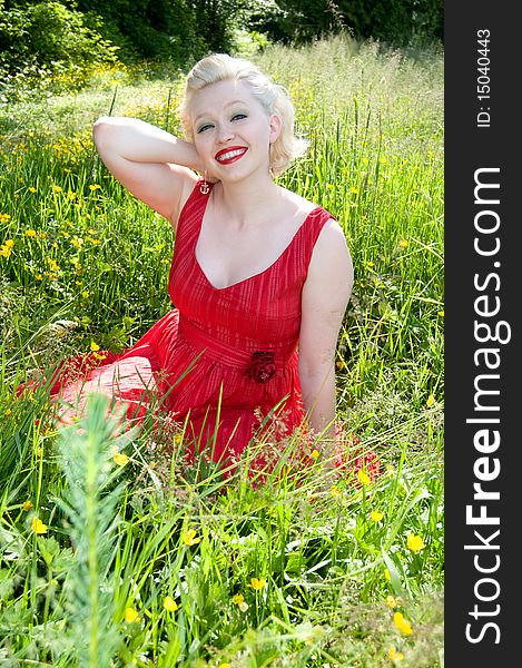Young woman sitting in a field of wildflowers. Young woman sitting in a field of wildflowers