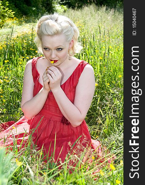 Young woman sitting in a field of wildflowers holding buttercup. Young woman sitting in a field of wildflowers holding buttercup