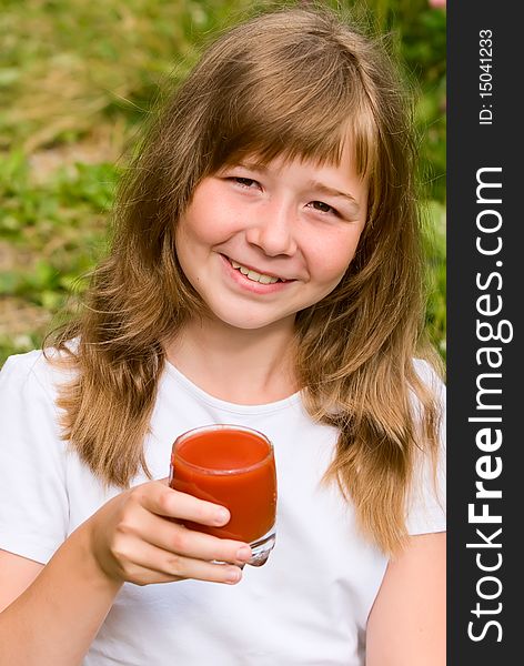 The girl holds a glass of tomato juice in a hand. The girl holds a glass of tomato juice in a hand