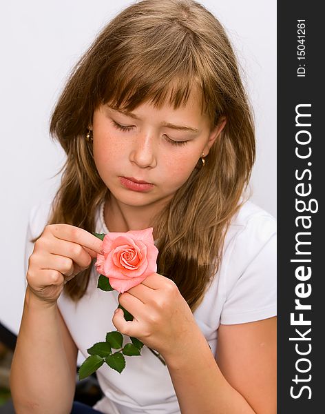 The portrait of the girl of the teenager in a white vest which holds the broken rose in a hand