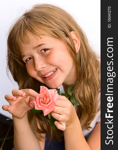 The portrait of the girl of the teenager in a white vest which holds the broken rose in a hand