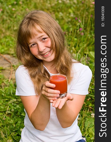 The girl holds a glass of tomato juice in a hand. The girl holds a glass of tomato juice in a hand