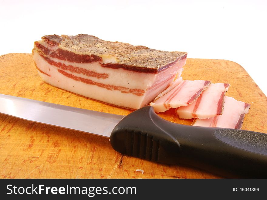 Knife with slices of bacon on a chopping board ready to be cooked. Knife with slices of bacon on a chopping board ready to be cooked