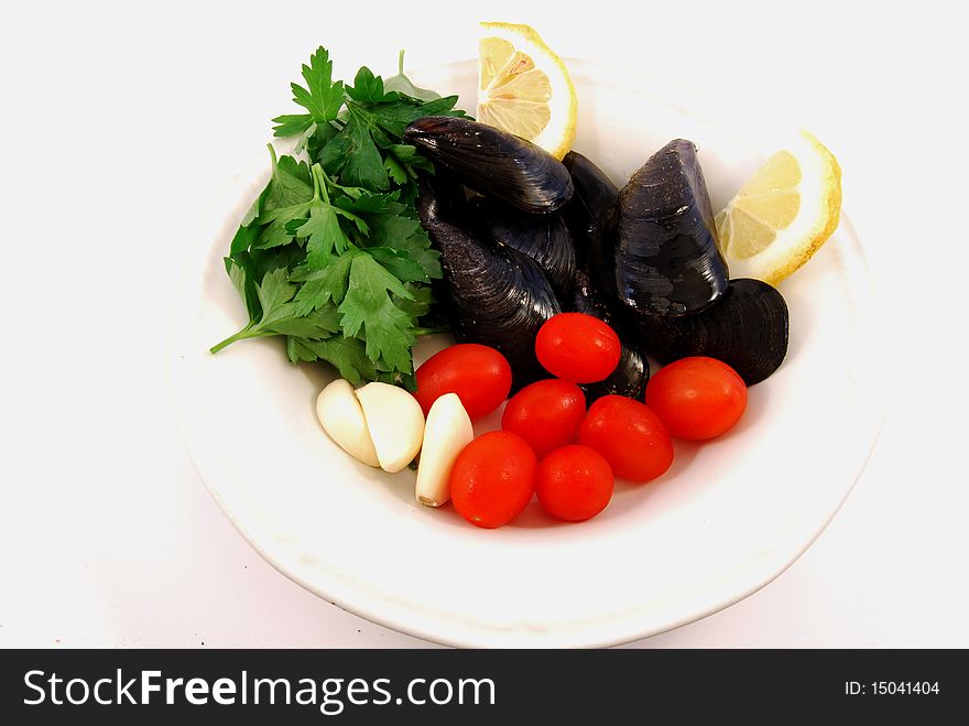 A plate of mussels ready to cook with lemon, tomato and  parsley
