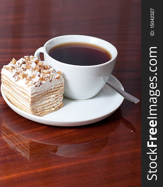 A cup of tea with a piece of cake on a plate. A cup of tea with a piece of cake on a plate