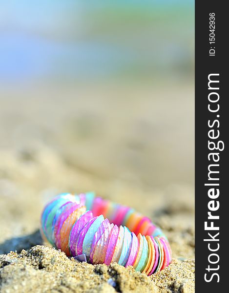 Shell bracelet on beach with sea background