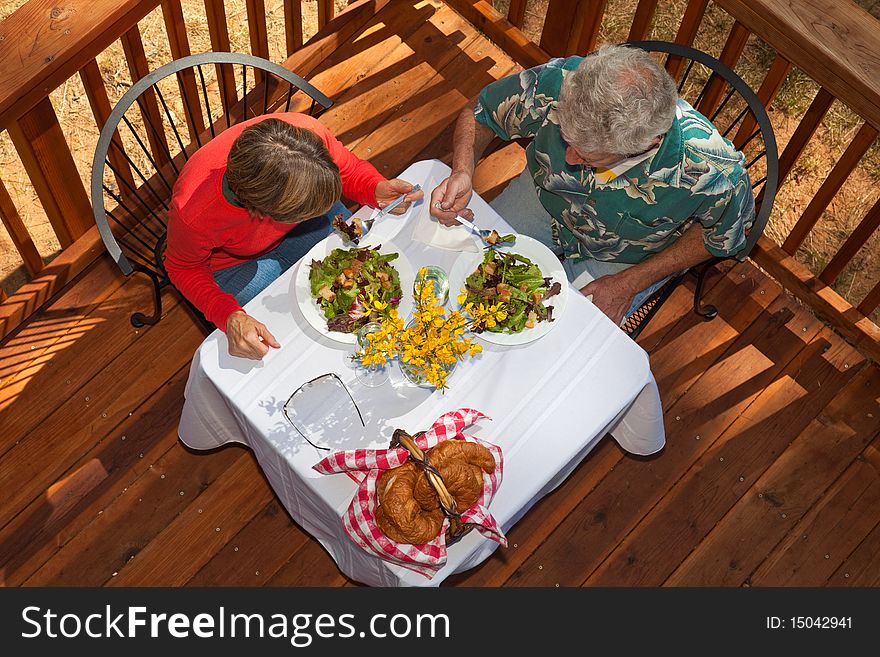 Middle aged couple having salad, croissants, and wine at an outdoor cafe. Middle aged couple having salad, croissants, and wine at an outdoor cafe.