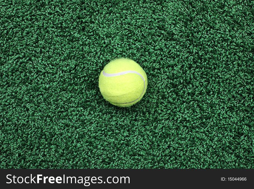 Yellow tennis ball on a green covering close up