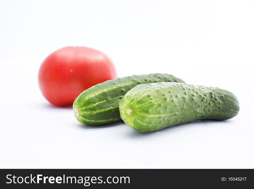 Red tomato and green cucumber on white background. Red tomato and green cucumber on white background