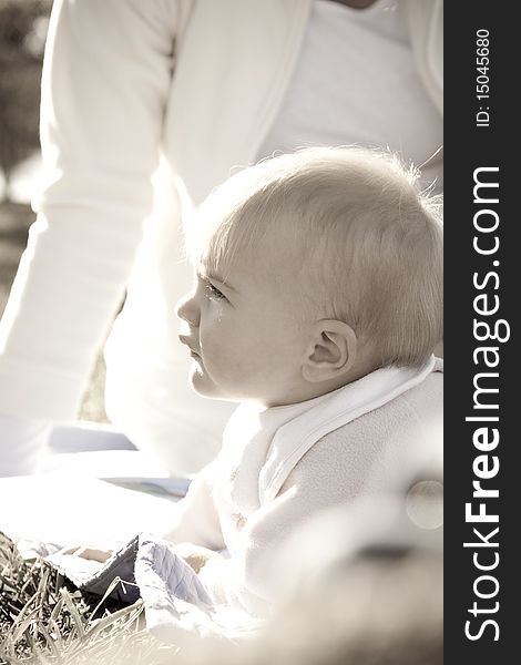 High key image of a baby enjoying the sun in a park with her mother