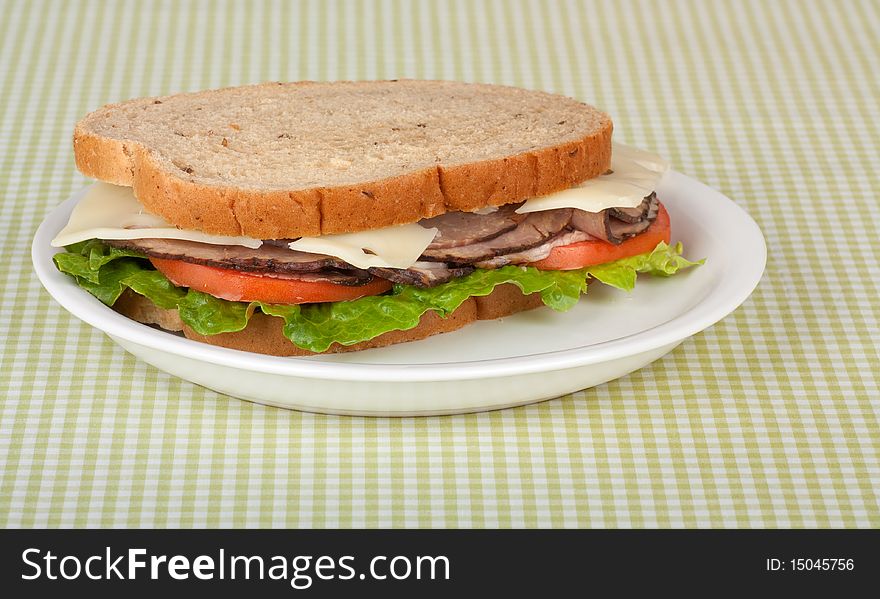 Roast beef sandwich on rye bread with swiss cheese, tomato, and lettuce