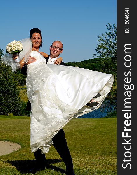 Groom is lifting his bride up in a park. Groom is lifting his bride up in a park.