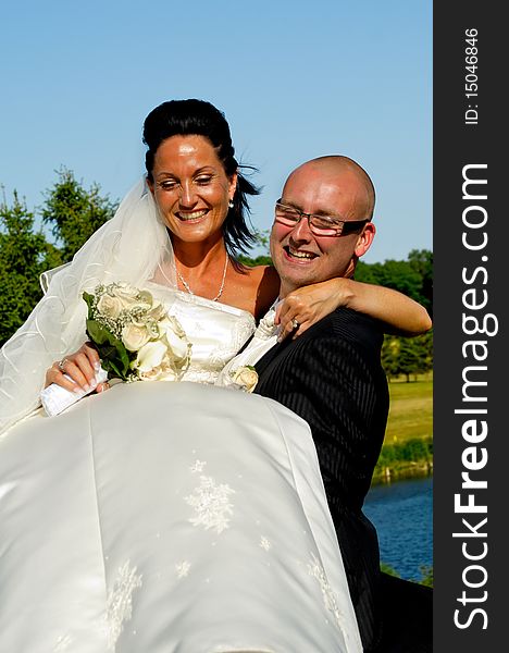 Groom is lifting his bride up in a park. Groom is lifting his bride up in a park.