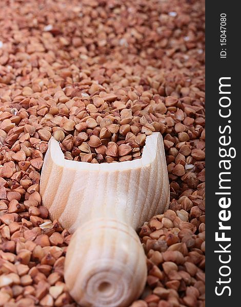 Buckwheat groats with a wooden deep spoon for packaging.