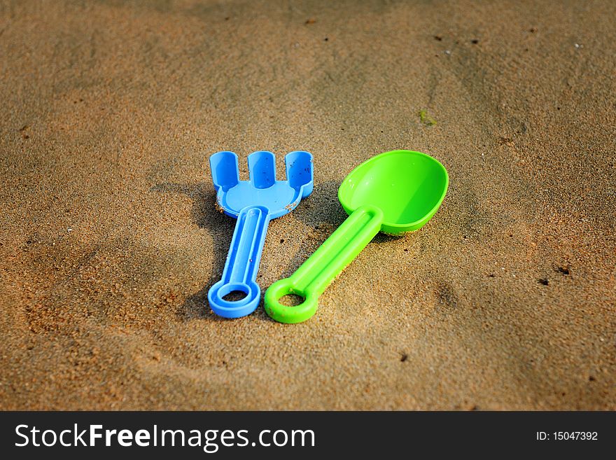 Toy spade and rake on beach sand. Toy spade and rake on beach sand