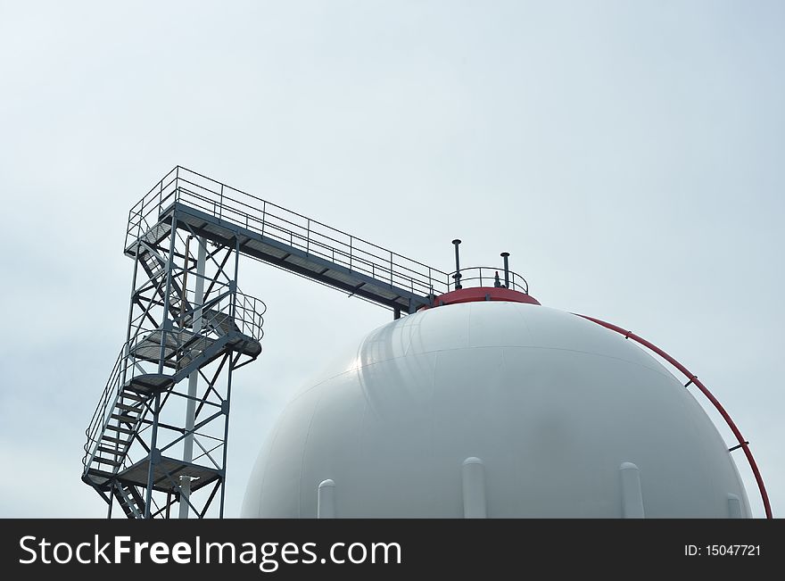 Oil reservoir detail with access ladder against a blue sky