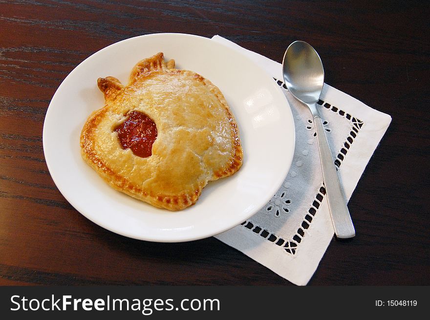 Apple shaped pastry served on a plate with spoon. Apple shaped pastry served on a plate with spoon