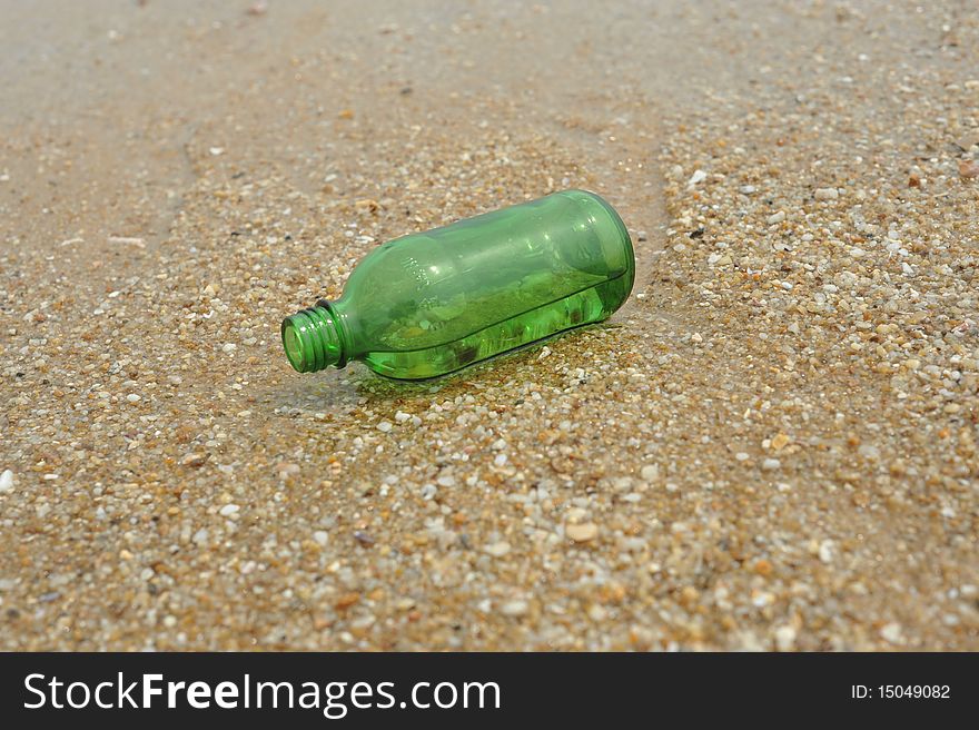 The Green empty Bottle lay on beach. The Green empty Bottle lay on beach