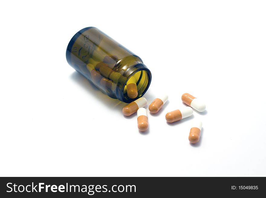 A few pills spilled out of a blank pillbox. A few pills spilled out of a blank pillbox