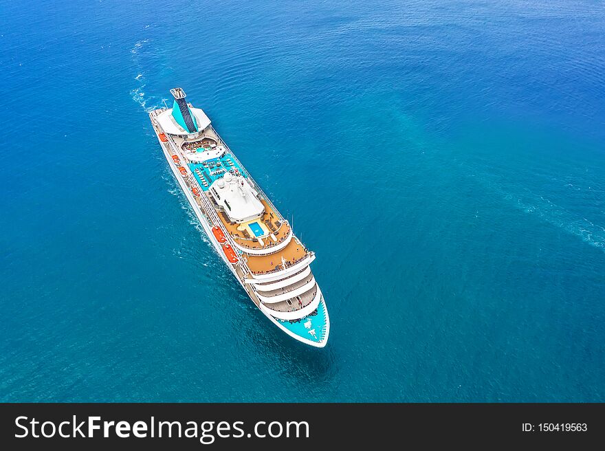 Cruise ship liner sails in the blue sea leaving a plume on the surface of the water seascape. Aerial view the concept of sea