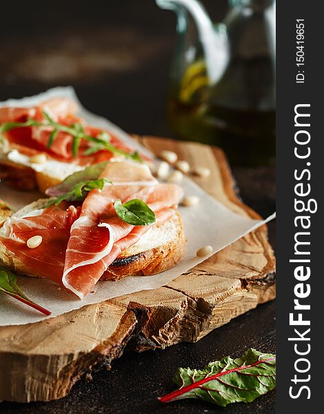 Traditional parma cured ham antipasto. Bruschetta set with Parma Ham and Parmesan Cheese. Small sandwiches with prosciutto