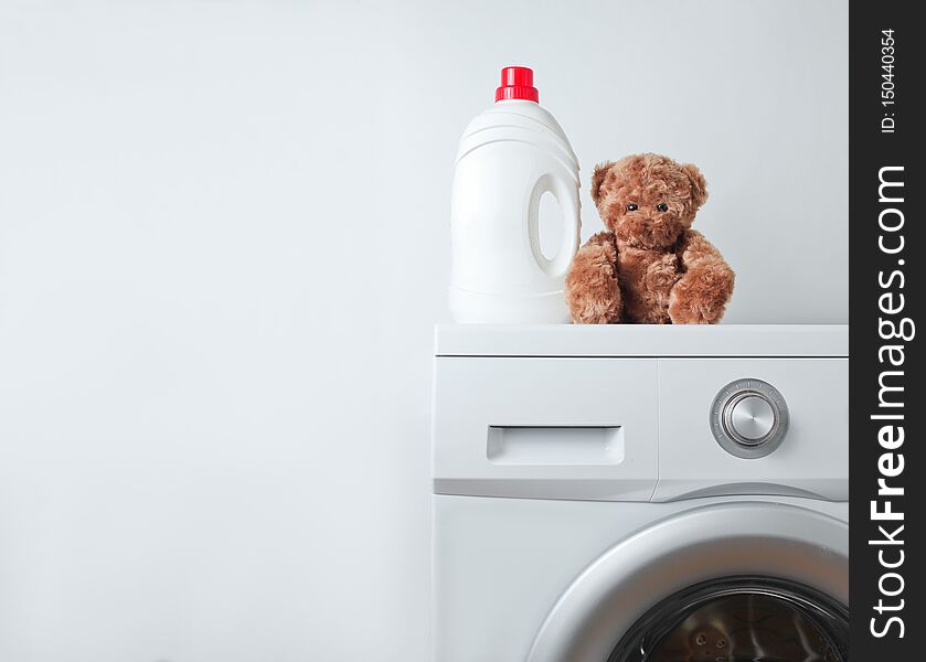 Bottle of liquid washing gel, teddy bear on a washing machine against a white background. Bottle of liquid washing gel, teddy bear on a washing machine against a white background