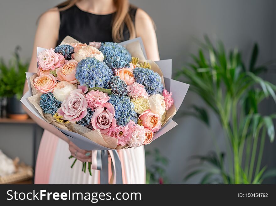 Beautiful bouquet of mixed flowers in woman hand. Floral shop concept . Handsome fresh bouquet. Flowers delivery. Blue