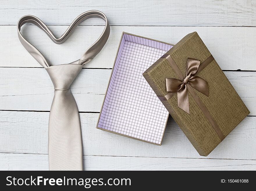 Gift box and necktie on wooden background.