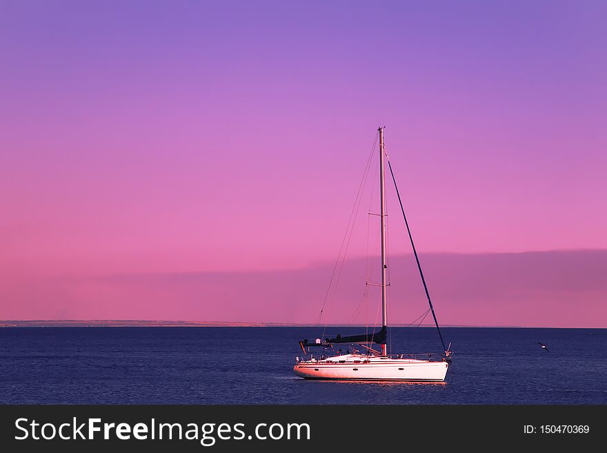 Red sunset over the blue sea, purple sky and yachts in the parking lot. Summer sea scenic landscape in the beautiful evening