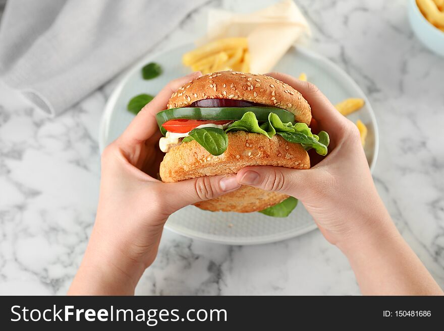 Woman Holding Tasty Burger Over Plate At Table