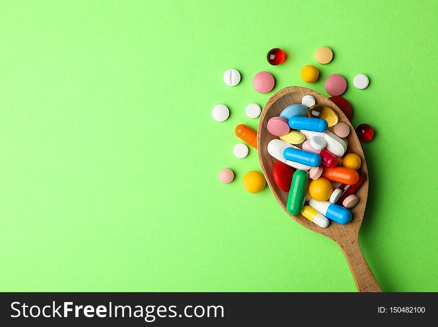 Spoon and pills on color background, top view with space for text